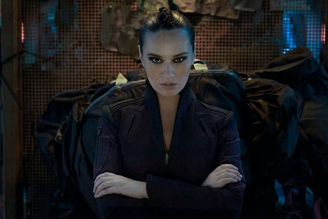 Drummer looks forward with an intense stare, in The Expanse, while sitting in the captains chair of her ship.  While not appearing in 'Exodus', Drummer appears more in 'Churn' and 'Mother'.