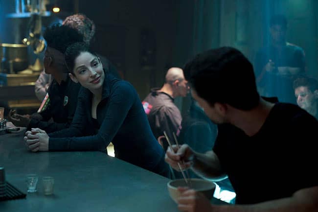Monica chats to Holden at a bar, in The Expanse.  She is standing leaning against the bar, while Holden sits and eats.  Holden isn't in 'Exodus' much, but appears more in 'Churn' and 'Mother'.