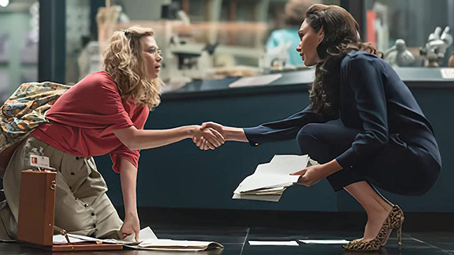 Barbara and Diana meet after Barbara drops all her papers.  Both are crouching down picking them up.  WW84